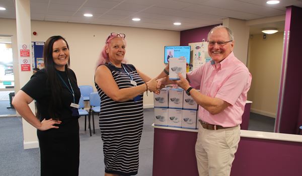 a photo of the practice manager and pharmacy technician tracey accepting blood pressure monitors from the ppg 