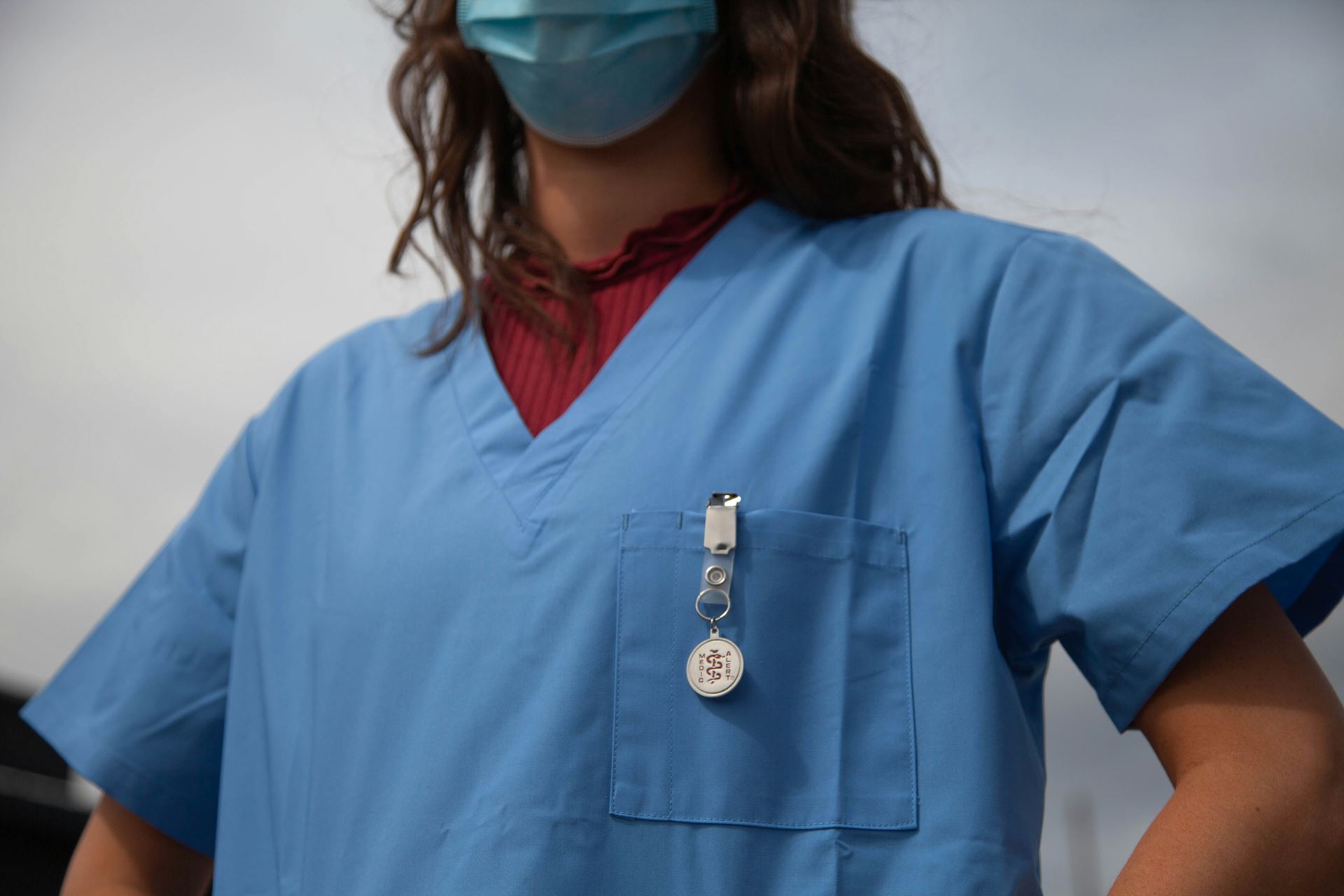 A person stood in scrubs and a mask